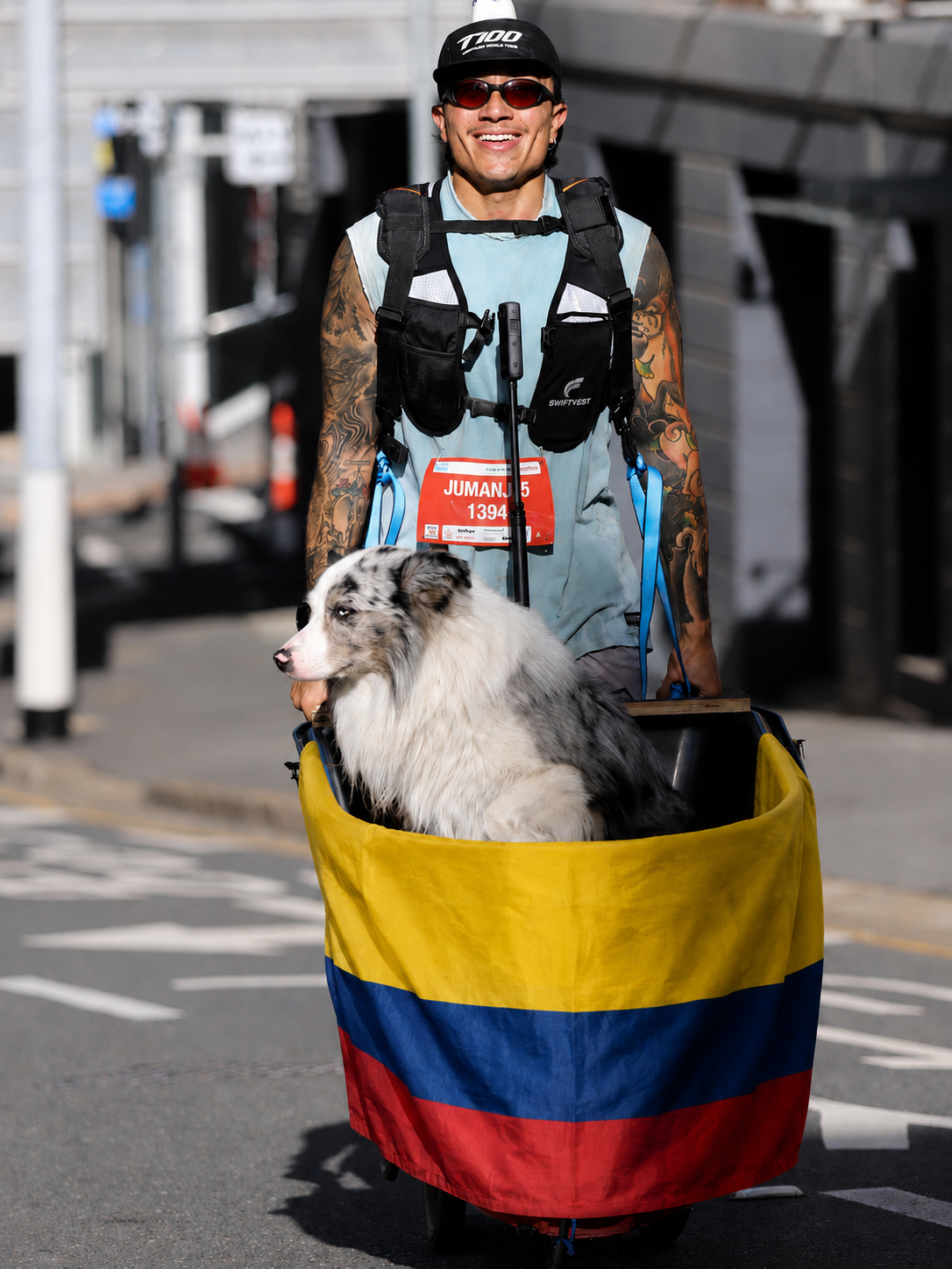 Jhoyner corriendo con su perro en un carrito cubierto con la bandera de Colombia